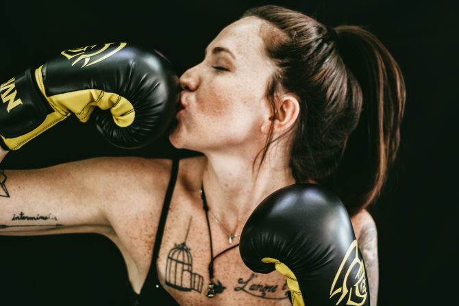 woman kissing black boxing gloves