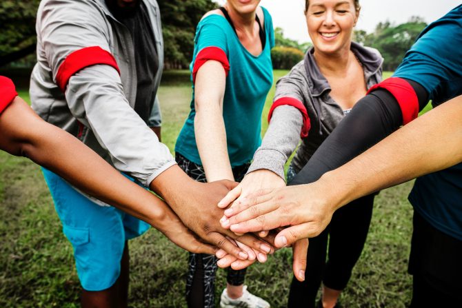 six people holding hands together at daytime