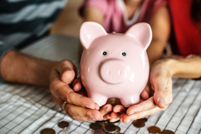 person holding pink ceramic pig coin bank