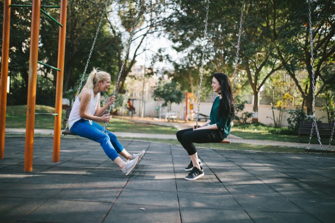 two women sitting on swings