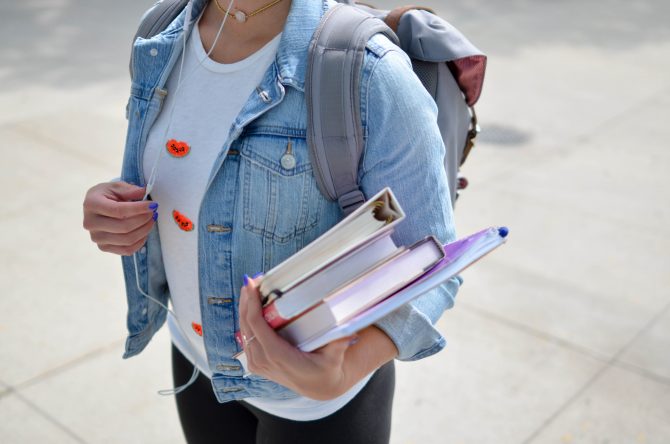 woman wearing blue denim jacket holding book, exams