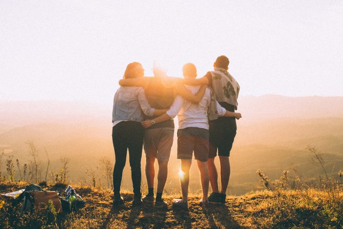 four people standing watching sunset