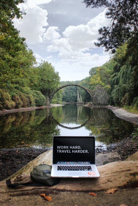 laptop by river "work hard, travel harder"