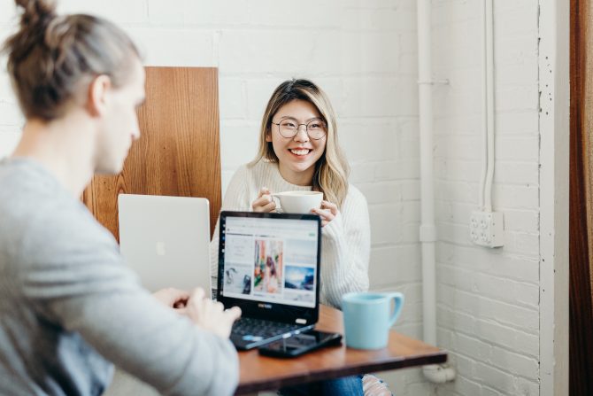 holding coffee while sitting in front of laptop