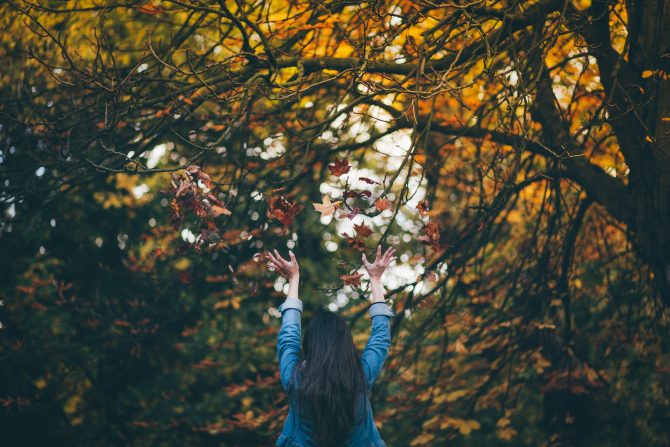 woman standing under changing leaves