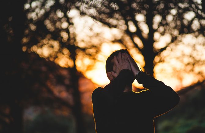 existing stress, man with hands over face outside