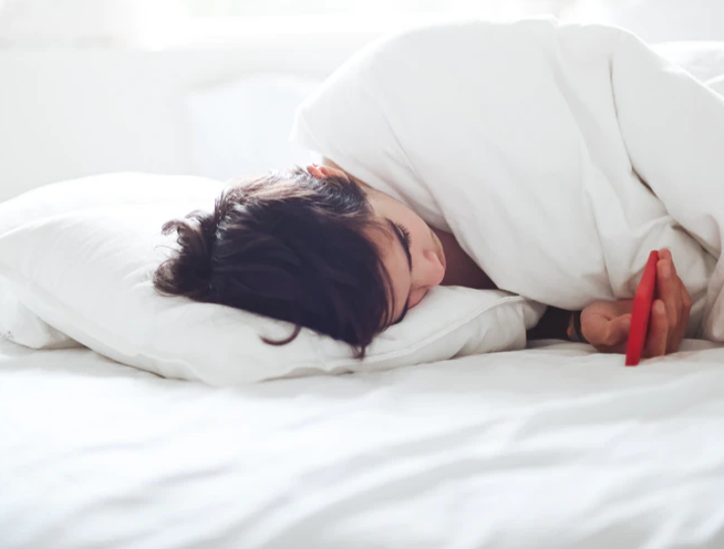 sleep routine, woman lying in bed with phone